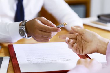 Belgeyi imzalayabilmek için kadın müşteriye kalem veren emlakçı