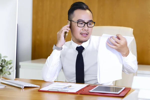 携帯電話を取る時に金融文書を読んで眼鏡でアジアの起業家 — ストック写真