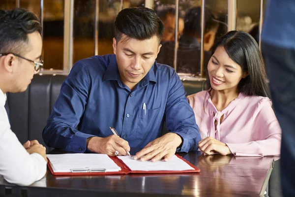 Homem Vietnamita Assinando Contrato Com Agente Imobiliário Quando Sentado Mesa — Fotografia de Stock