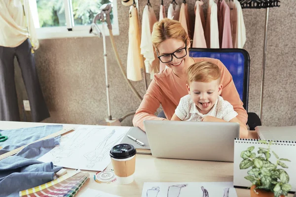 Vrolijke Vrouwelijke Modeontwerper Werkt Laptop Met Zoon Haar Ronden — Stockfoto