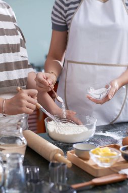 Kurabiye hamuru yaparken kaseye malzeme ekleyerek anne ve kızı yakın çekim görüntü