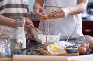 Genç kızın elleri kurabiye hamuru ile kasede taze yumurta çatlama