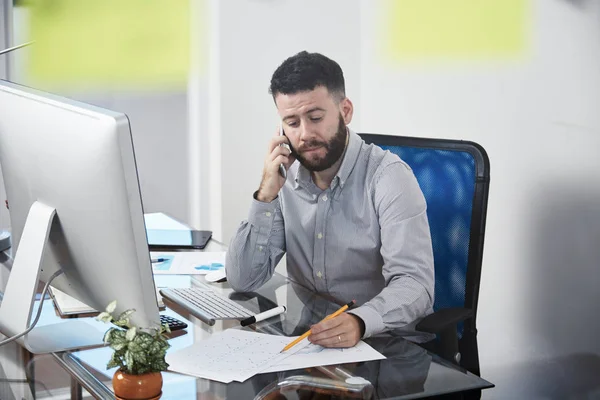 Gerente Barbudo Grave Sentado Local Trabalho Examinando Documentos Falando Telefone — Fotografia de Stock