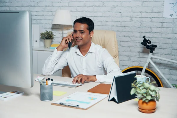 Индийский Менеджер Сидит Своем Рабочем Месте Печатая Клавиатуре Компьютера Разговаривая — стоковое фото