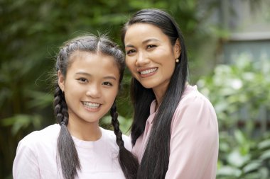 Asya güzel anne portresi kızı ile birlikte ayakta ve kamera gülümseyerek