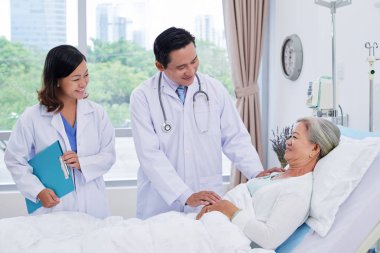 Vietnamlı doktor ve hemşire ameliyat sonrası yaşlı kadın ziyaret