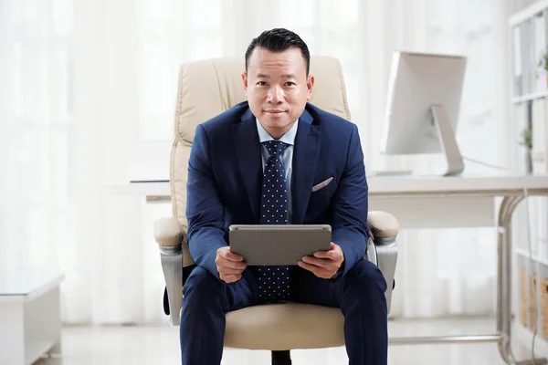 Portrét Sebevědomého Asijského Obchodníka Sedícího Židli Digitálním Tabletem Který Dívá — Stock fotografie