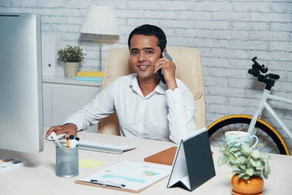 Ofiste Cep Telefonuyla Konuşurken Bilgisayar Önünde Işyerinde Oturan Kameraya Bakan — Stok fotoğraf