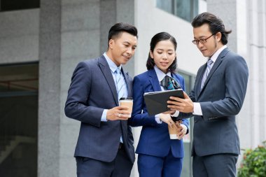 iki işadamı ve kadın açık havada duran ve dijital tablet kullanarak 