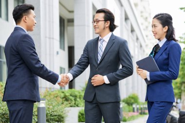 El sıkışırken duran işadamları ve tablet pc tutan kadın asistan ve şehirde onlara bakarak