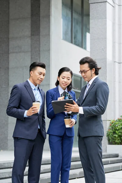 Young Asian Businesswoman Typing Tablet Two Businessmen Standing Her Looking — Stock Photo, Image