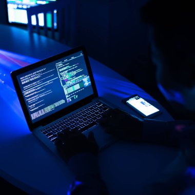Dizüstü bilgisayar ve neon parlayan karanlıkta oturan güvenlik sistemi hack kullanarak adam Kırpma atış
