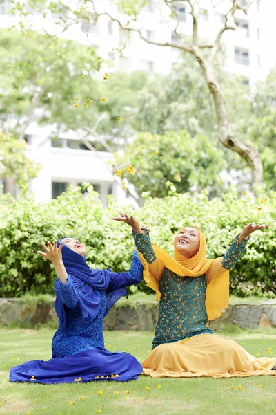 Mujeres Musulmanas Felices Sentadas Préstamo Lanzando Pétalos Flores Amarillas Aire —  Fotos de Stock