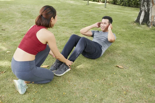 Young Woman Holding Feet Her Friend Who Doing Crunches Ground — Stock Photo, Image