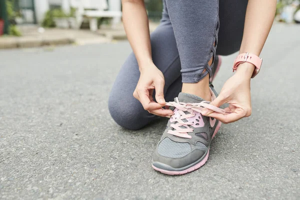 屋外でジョギングする前に靴ひもを結ぶ女性のクローズアップ画像 — ストック写真
