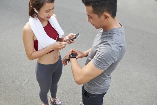 Jóvenes Deportistas Vietnamitas Revisando Aplicaciones Teléfonos Inteligentes Relojes Inteligentes Después —  Fotos de Stock