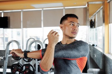 Kendine güvenen Vietnamlı sporcu portre eğitim öncesi ısınmak için silah germe