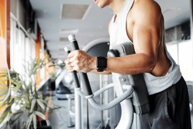 Spor salonunda fitness makinesi üzerinde egzersizler yapan kaslı adam Kırpılmış görüntü