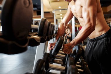 Raftan dumbbell alarak ve spor salonunda eğitim gidiyor gömleksiz vücut geliştirmeci Yakın Çekim