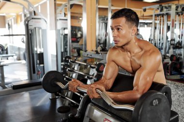 Asya kaslı adam spor salonunda barbell ile yoğun egzersiz yapıyor