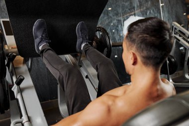 Genç gömleksiz atlet bacak pres makinesi nde bacakları ile ağırlık yükselterek ve sağlık kulübünde bacaklarını eğitim