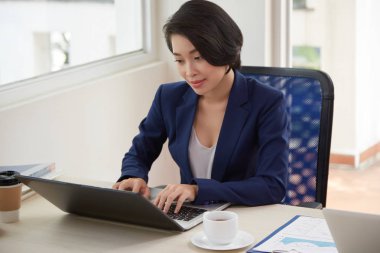 Genç yönetici masada oturan ve ofiste onu iş günü boyunca dizüstü bilgisayarda yazma