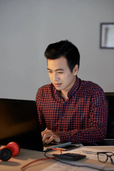 英俊的年轻亚洲男子在格子衬衫编程在笔记本电脑 — 图库照片