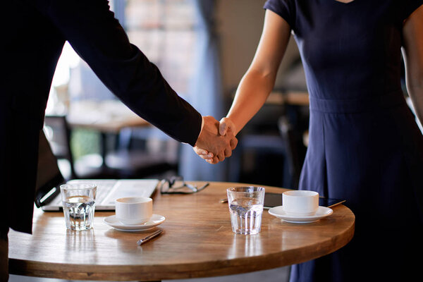 Обрезанный образ предпринимателя, пожимающего руку деловым партнерам перед встречей в кафе
