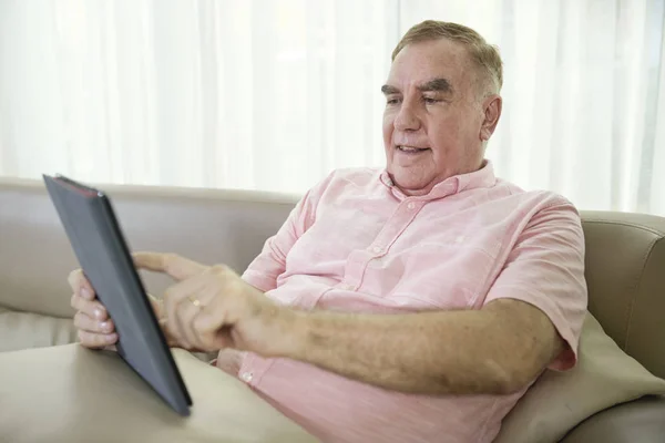 快乐的老人在家沙发上休息 在平板电脑上使用应用程序 — 图库照片