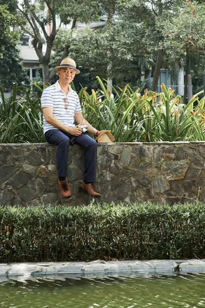 Portrait Asian Senior Photographer Sitting Stone Wall Pond Using Photo — Stock Photo, Image