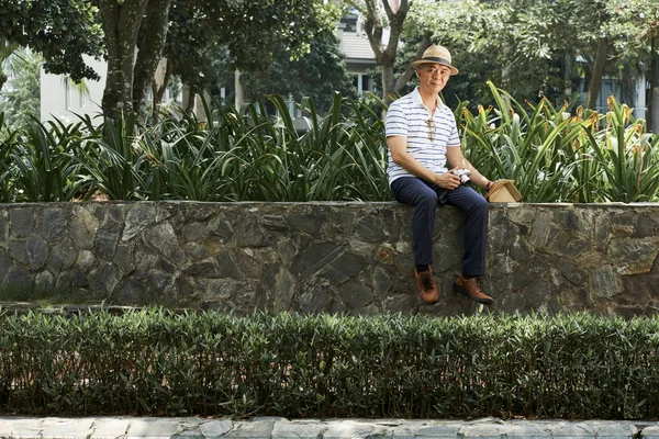 Портрет Азиатского Человека Шляпе Сидящего Каменной Стене Планшетным Цифровой Камерой — стоковое фото