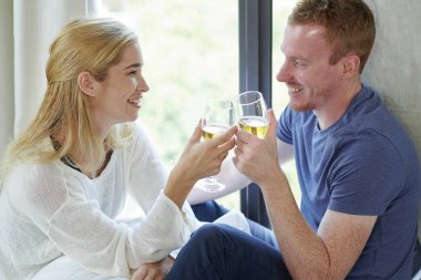 Mutlu erkek arkadaşı ve kız arkadaşı köpüklü şarap kadehleri ile birbirlerine sevgiile bakıyor