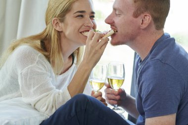 Aşık mutlu genç çift lezzetli pizza aynı dilim paylaşımı ve şarap içme