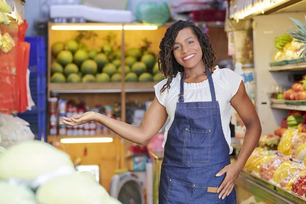 Smiling pretty saleswoman inviting you to supermarket with fresh organic fruits and vegetables