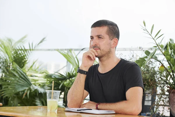 Jeune Homme Assis Table Devant Bloc Notes Ouvert Réfléchissant Nouvelles — Photo