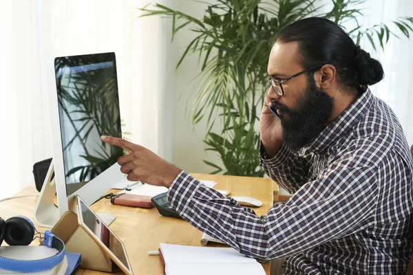 Bebaarde Jonge Zakenman Wijst Computer Monitor Praat Mobiele Telefoon Tijdens — Stockfoto