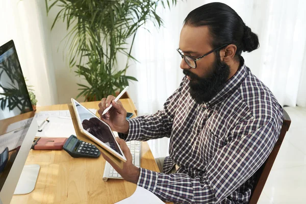 Jovem Designer Barbudo Óculos Sentado Mesa Olhando Para Exibição Tablet — Fotografia de Stock