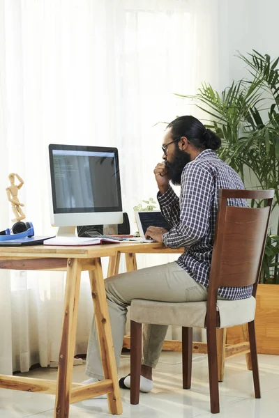 Freelancer Barbudo Sério Sentado Mesa Examinando Novo Software Monitor Computador — Fotografia de Stock