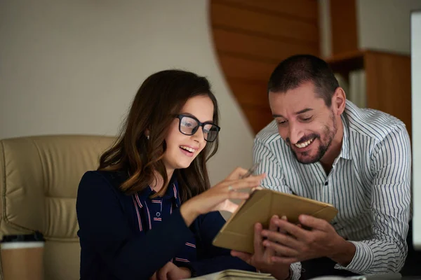 Cheerful young business people discussing information on screen of tablet computer