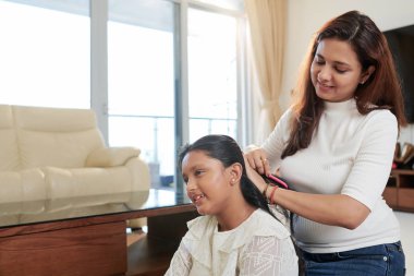 Mutlu anne kızının siyah uzun saçları tarama ve evde sabah ona bir saç modeli yapıyor