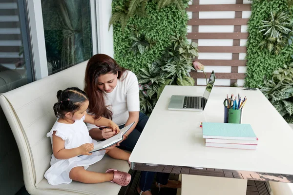 Joven Madre Enseñando Hija Escribir Cuaderno Mientras Sientan Sofá Aire — Foto de Stock