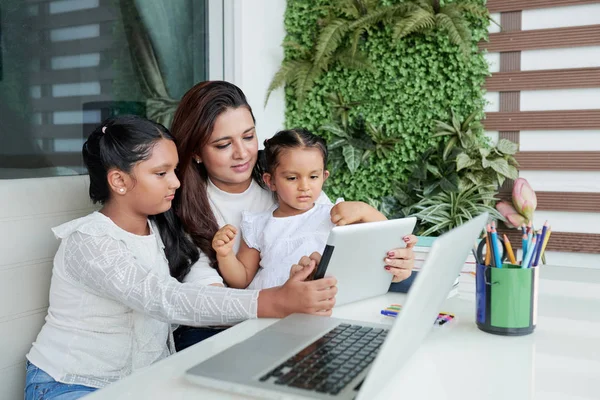 母亲和她的小女儿和年长的女儿坐在一起坐在一起 他们在家里的空闲时间一起使用数字平板电脑 — 图库照片