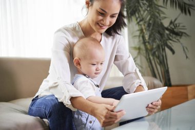Neşeli genç karışık ırk kadın ve onun küçük oğlu dijital masada animasyon izliyor