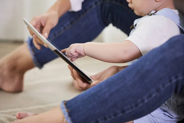 母親は 彼女の赤ちゃんの男の子と自宅でうろつきに座って タブレットコンピュータ上で彼の教育アプリケーションを示しています — ストック写真