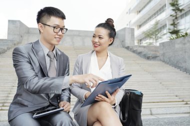 Gülümseyen genç işadamı, iş sözleşmesini işaret eden ve gülümseyen iş kadını yla birlikte tartışan tablet pc ile gözlüklü genç işadamı 