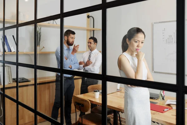 Asyalı Kadını Ofiste Ayakta Düşünme Meslektaşları Arkasından Konuşurken — Stok fotoğraf