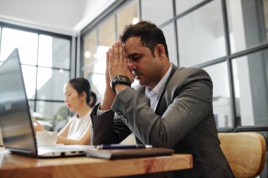 Hintli işadamı dizüstü bilgisayar ile masada otururken gözleri kapalı ve istirahat süre iş kadını ofiste ona yakın çalışan