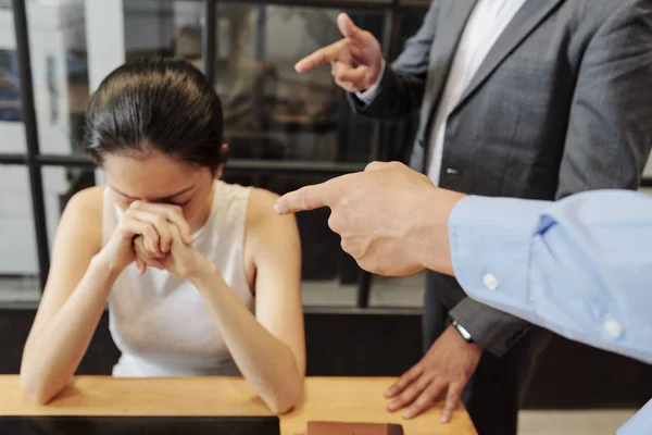 悲伤的女商人坐在桌旁 而她的同事指着她 指责她会议失败 — 图库照片