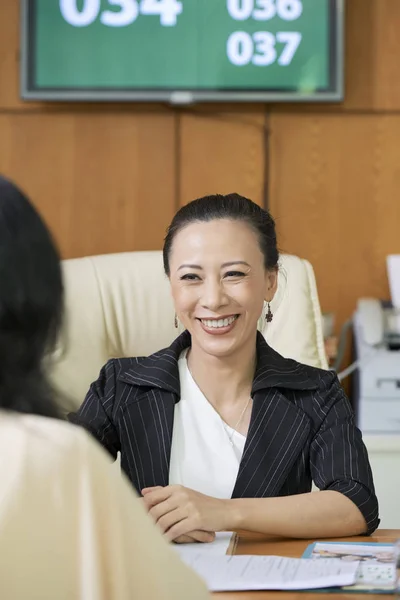 Asiático Jovem Assistente Social Sentado Mesa Sorrindo Enquanto Conversa Com — Fotografia de Stock