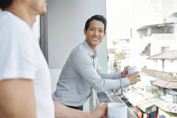 Веселый Молодой Вьетнамский Бизнесмен Кружкой Кофе Слушает Шутку Своего Коллеги — стоковое фото